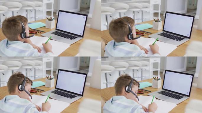 快乐的高加索男孩在网上学校课程中使用耳机和笔记本电脑，在屏幕上复制空间
