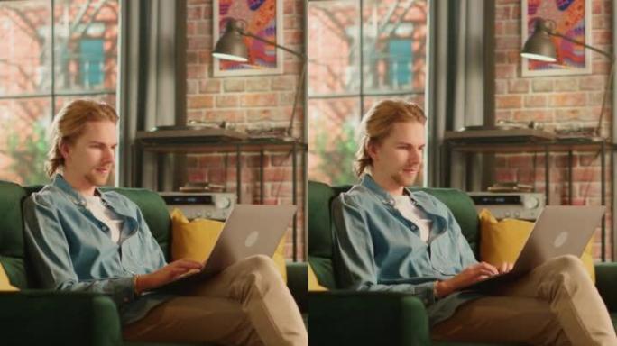 垂直屏幕: 年轻英俊的男人坐在阁楼公寓的沙发上，在家使用笔记本电脑工作。创意男性查看社交媒体，浏览互