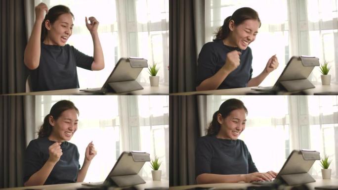 慢动作亚洲女人在家用笔记本电脑庆祝我的成功