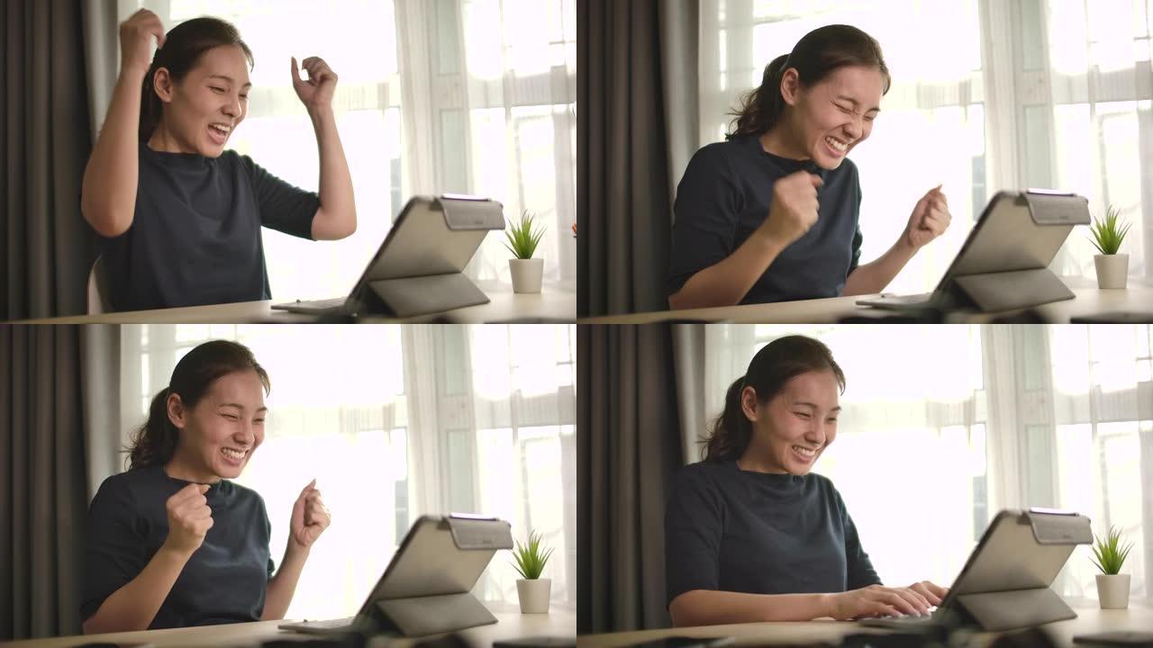 慢动作亚洲女人在家用笔记本电脑庆祝我的成功