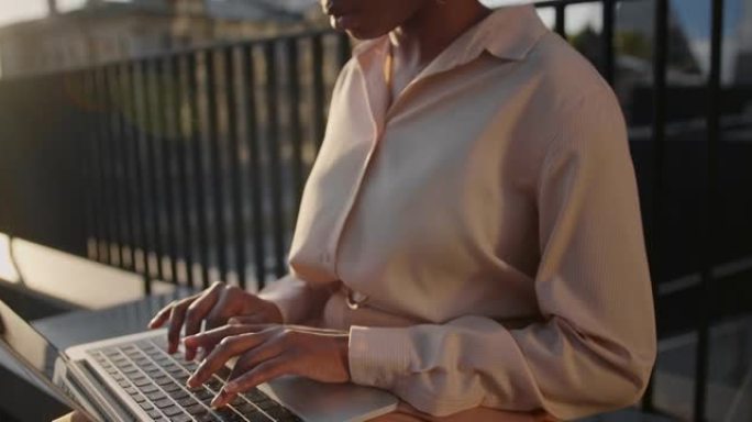 一位商务女士的手在美丽的傍晚阳光下在笔记本电脑上向伴侣输入电子邮件