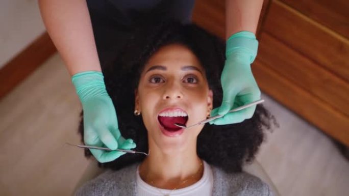 牙医从上方检查牙科预约期间女性患者的口腔。非洲妇女进行例行检查以防止蛀牙和牙龈疾病。良好的口腔卫生意