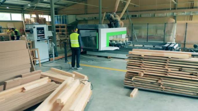 男工人检查木工工厂机器切割木材。