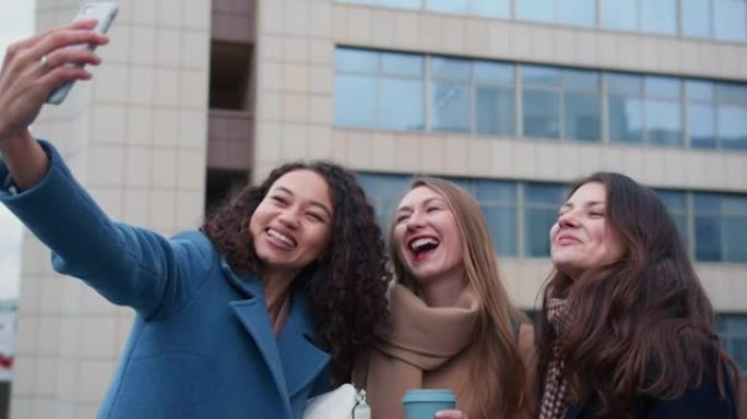 美丽兴奋快乐的年轻女性微笑着，在城市背景下使用智能手机拍照。