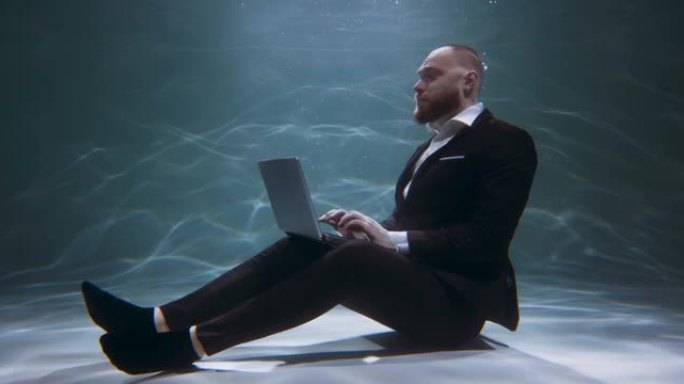 自由职业自我隔离。穿着西装的商人在水下观看电影，使用笔记本电脑慢动作。
