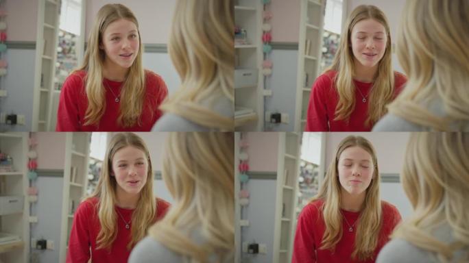 十几岁的女儿穿着睡衣坐在床上与母亲在卧室里说话的肩膀上-慢动作拍摄