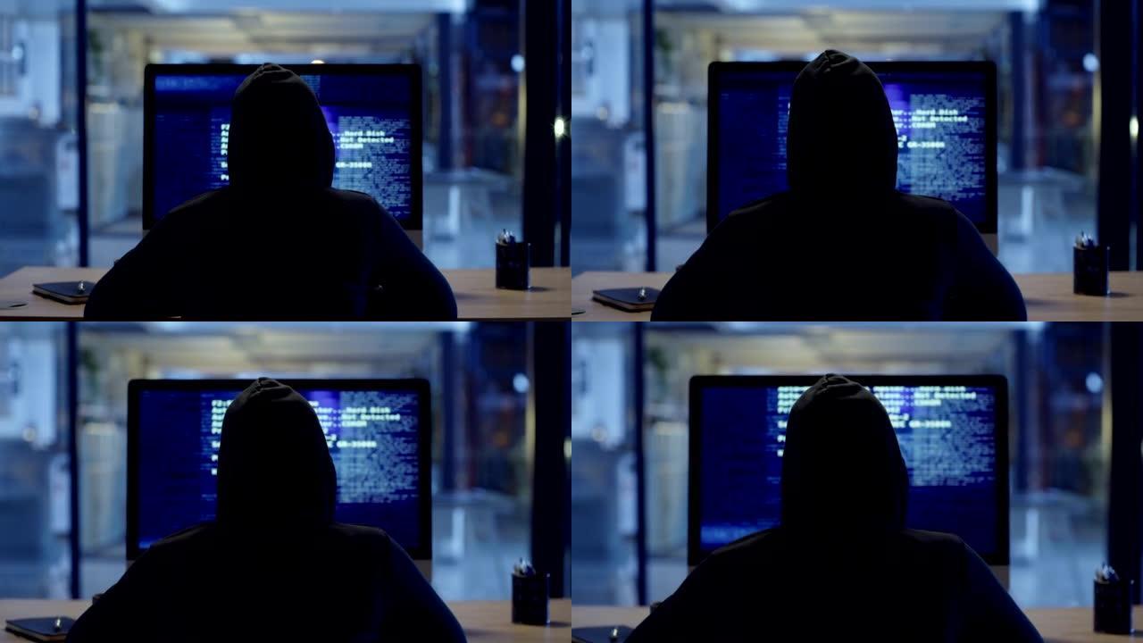 黑客或网络犯罪分子晚上坐在电脑上在线窃取信息。蒙面神秘人编码间谍软件、恶意软件和病毒，以实施欺诈、盗