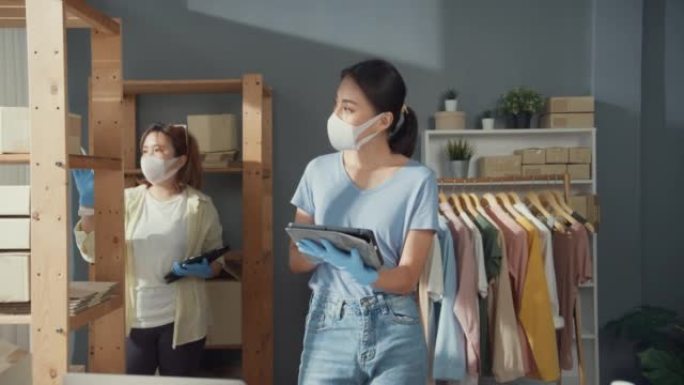 专业迷人开朗的两个亚洲女士老板青少年与休闲手术口罩保持平板电脑检查库存产品控制交付货物客户订单准备新