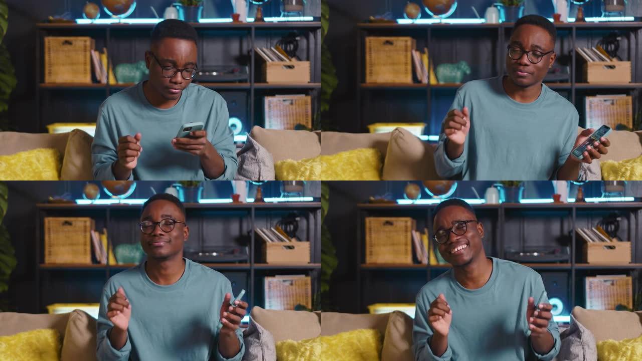 快乐成功的黑人男性博客作者庆祝win玩手机游戏，在bright home使用手机应用程序在线购物。