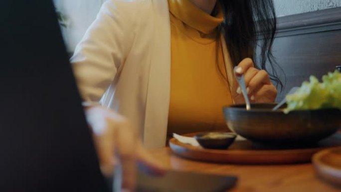 亚洲女商人在餐馆工作期间吃饭。