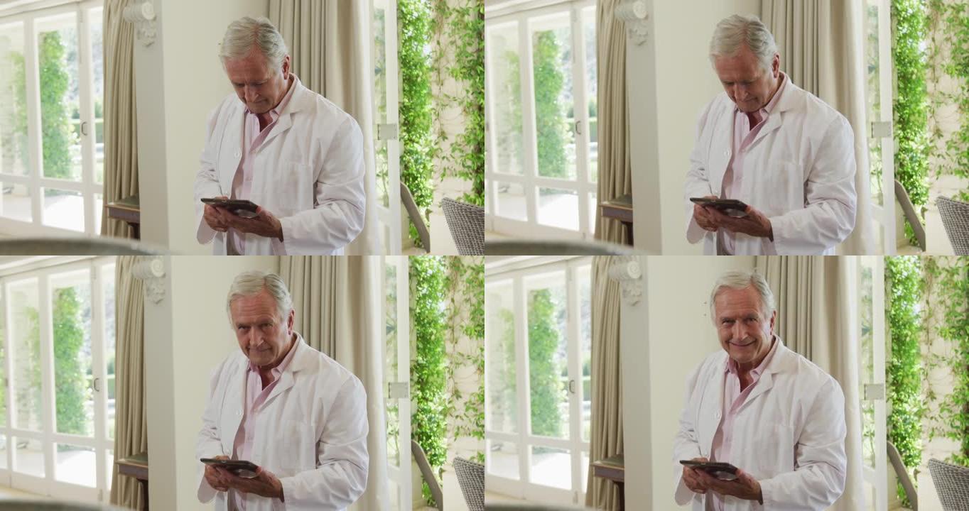 白人高级男医生在家里使用数字平板电脑时微笑的肖像