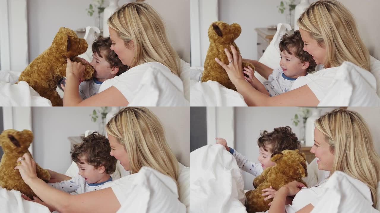 母亲在卧室里，小儿子穿着睡衣和玩具狗一起玩