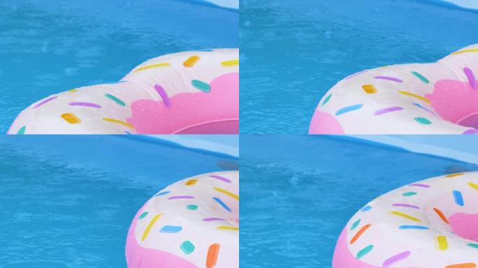 特写: 雨水开始倾泻在漂浮在游泳池周围的充气甜甜圈上。