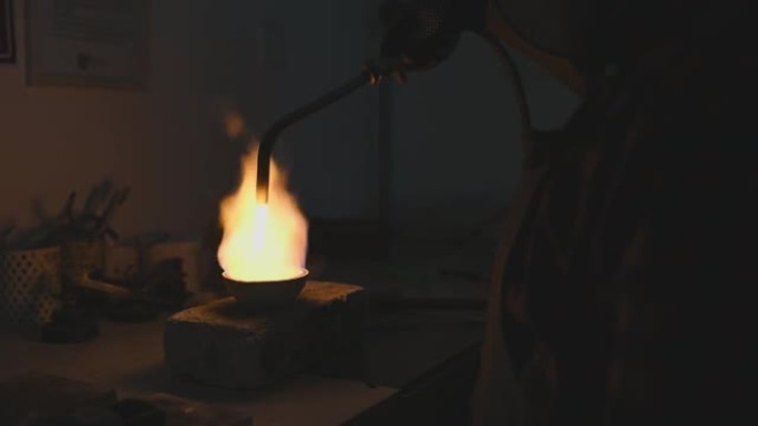 中东金匠珠宝商的手用火炬在陶瓷锅中熔化银金属