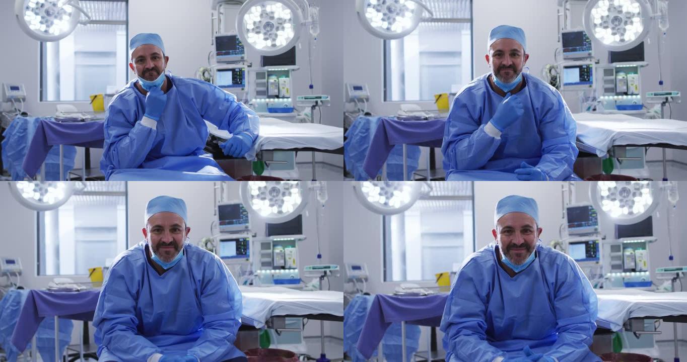 白人男性外科医生的肖像戴着低面罩坐在手术室里微笑