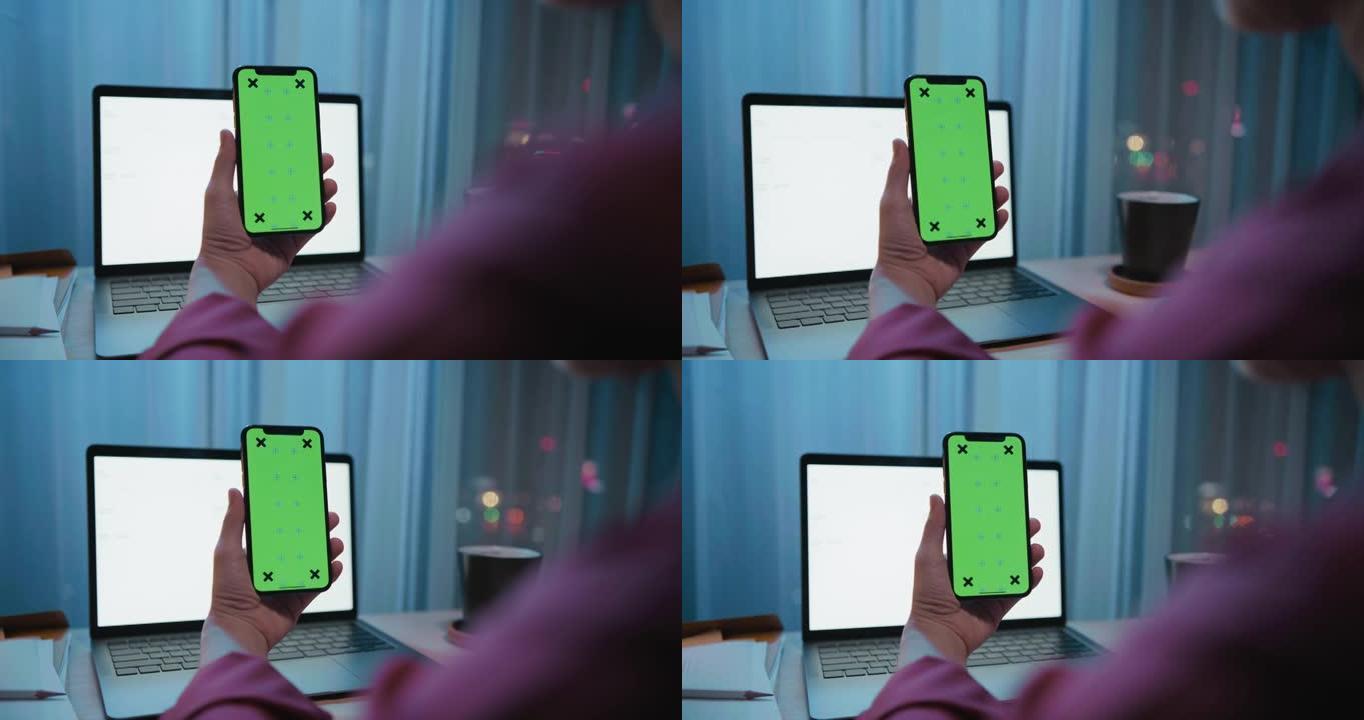 女人在带有绿屏模型的笔记本电脑上使用手机拍摄的照片