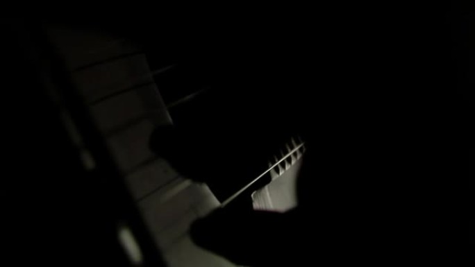 男人的手在黑暗的房间里弹吉他。特写。