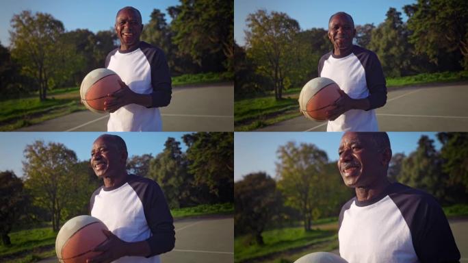非裔美国高级男子站在户外球场上与篮球微笑