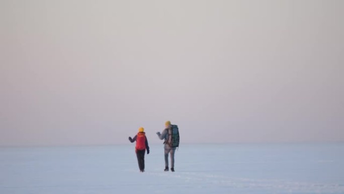 背着背包的男人和女人在雪域中穿行。慢动作