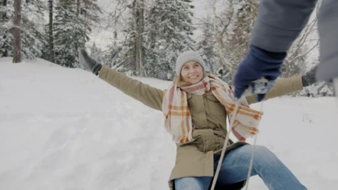 快乐的女士在冬天的森林里拉着雪橇享受骑行的肖像