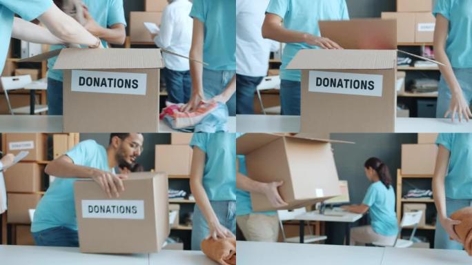 捐赠纸板箱的特写镜头和人手为慈善事业放衣服