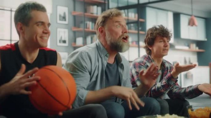 在家里，三个快乐的篮球迷坐在电视上的沙发上观看比赛，庆祝得分，他们的运动队冠军胜利。一群朋友欢呼，为