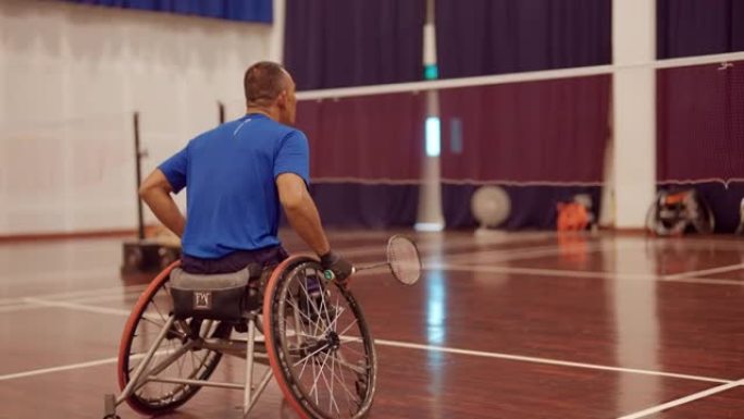 亚洲男子在室内网球场玩和练习轮椅羽毛球。