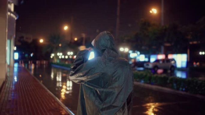 年轻人在下雨的时候穿上雨衣，在潮湿的天气里走回家