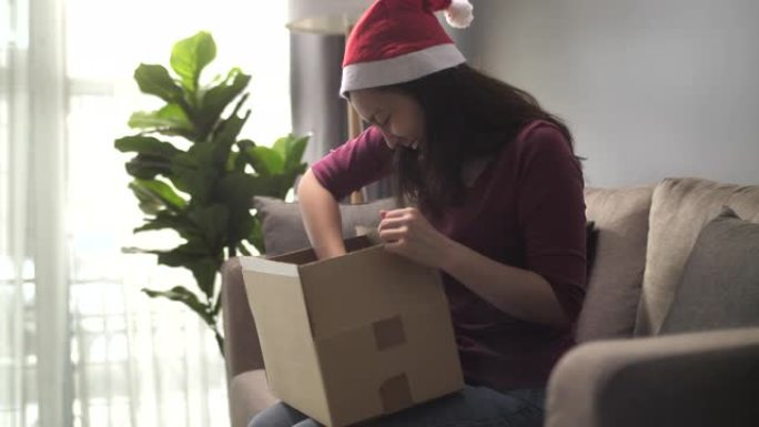 在圣诞节活动中，亚洲妇女在家中收到包裹和打开盒子