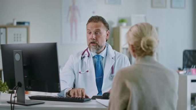 友好开朗的家庭医生正在健康诊所咨询期间阅读高级女性患者的病史。医生在医院办公室使用计算机。