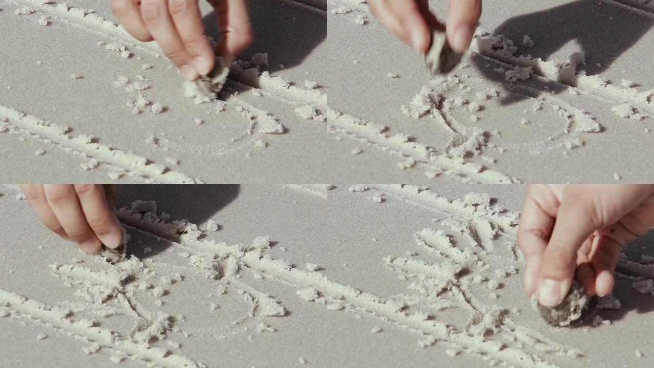 一名十几岁的女孩的手在福克兰群岛海滩上的白色沙滩上绘制的阿根廷国旗上画了五月的太阳。特写。