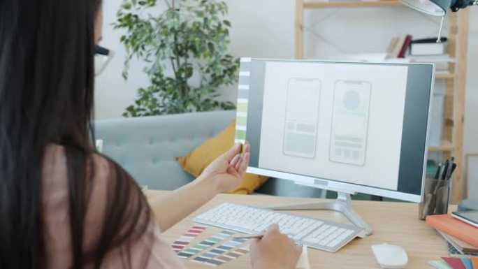 女性专家设计移动应用界面看着电脑屏幕拿着调色板在家工作