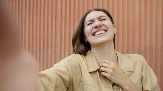幸福女人的肖像在街上打在线视频电话在户外笑