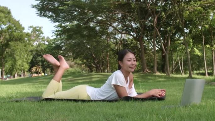 女子在户外做瑜伽与网上教程电脑