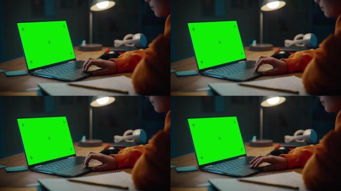 聪明的小男孩在绿屏显示的笔记本电脑上研究作业。青少年浏览教育研究，在笔记本上写作，学习教材。