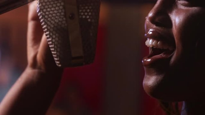 非裔美国女艺术家在音乐工作室的麦克风上唱歌