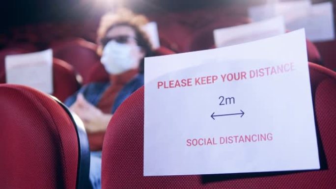 电影院大厅里有一个男人，座位上有社交距离的迹象