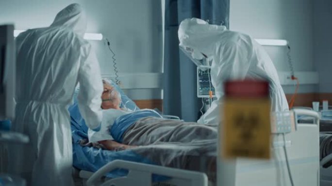 医院冠状病毒急诊科病房: 医生穿着工作服，戴口罩救人的一名高龄患者躺在床上，戴上氧气面罩并连接静脉滴