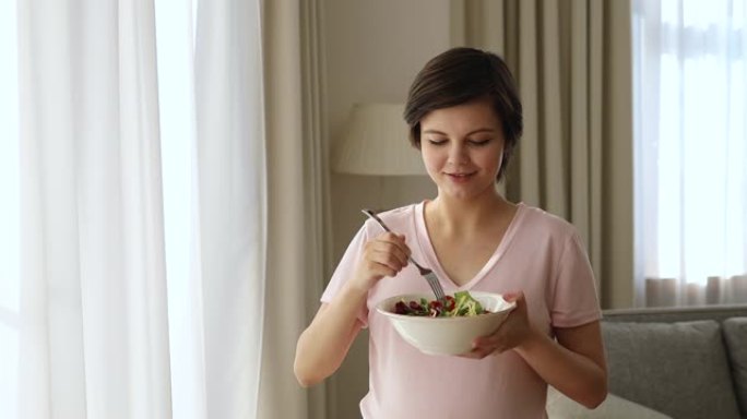 迷人的年轻孕妇拿着一碗蔬菜沙拉