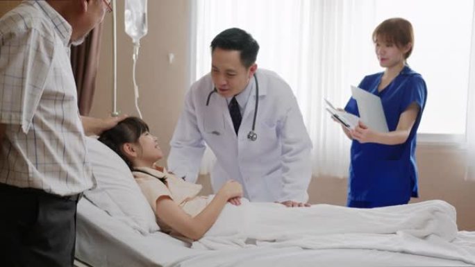 亚洲友好的医生男子与父母和可爱的小孩病人躺在病床上，检查健康。儿童医院儿科病房。医生随访病情患者。