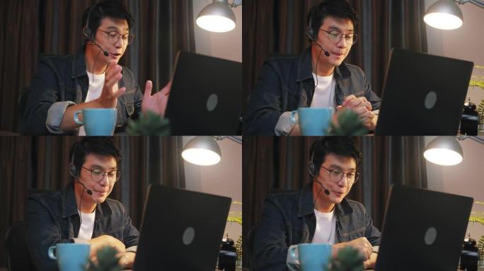 亚洲男子在视频电话会议期间使用笔记本电脑在家工作到很晚