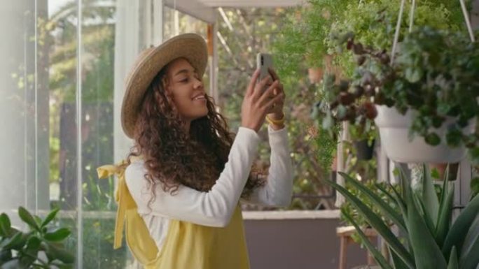 年轻的西班牙裔女花店在苗圃用手机拍摄植物照片