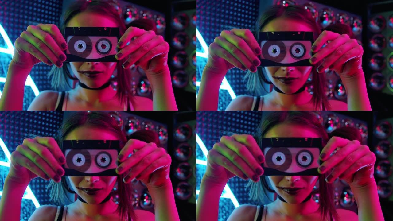 黑暗霓虹灯房间里的俱乐部女人通过复古音乐盒特写看相机。成人表演者女孩为DJ表演混合立体声轨道的复古旋