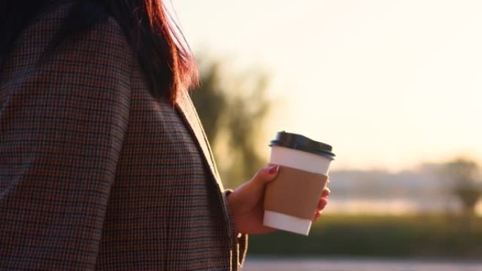 女子手持纸咖啡杯晨间散步