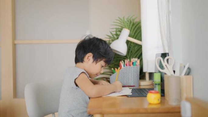 孩子在家学习。在书桌上写作业写写画画小男