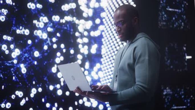 在笔记本电脑上工作的年轻黑人的肖像，看着显示神经网络可视化3D动画的大数字屏幕。分析用户信息的专业数