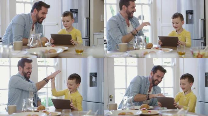一个小男孩使用数字平板电脑并在早餐桌上给父亲击掌的4k视频片段