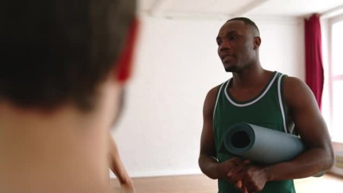 非洲男子在健身房与瑜伽课小组交谈