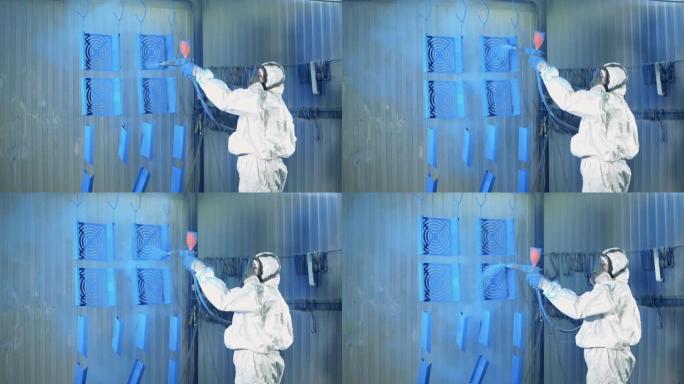 一名女工将蓝色油漆喷在金属板上。涂装工厂设施的工业涂装工艺。