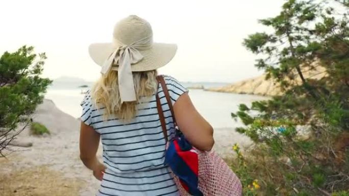 意大利撒丁岛夏季，一名金发女子在海滩上散步的景色。